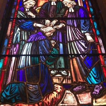 Stained glass window with religious figures in jewel tones